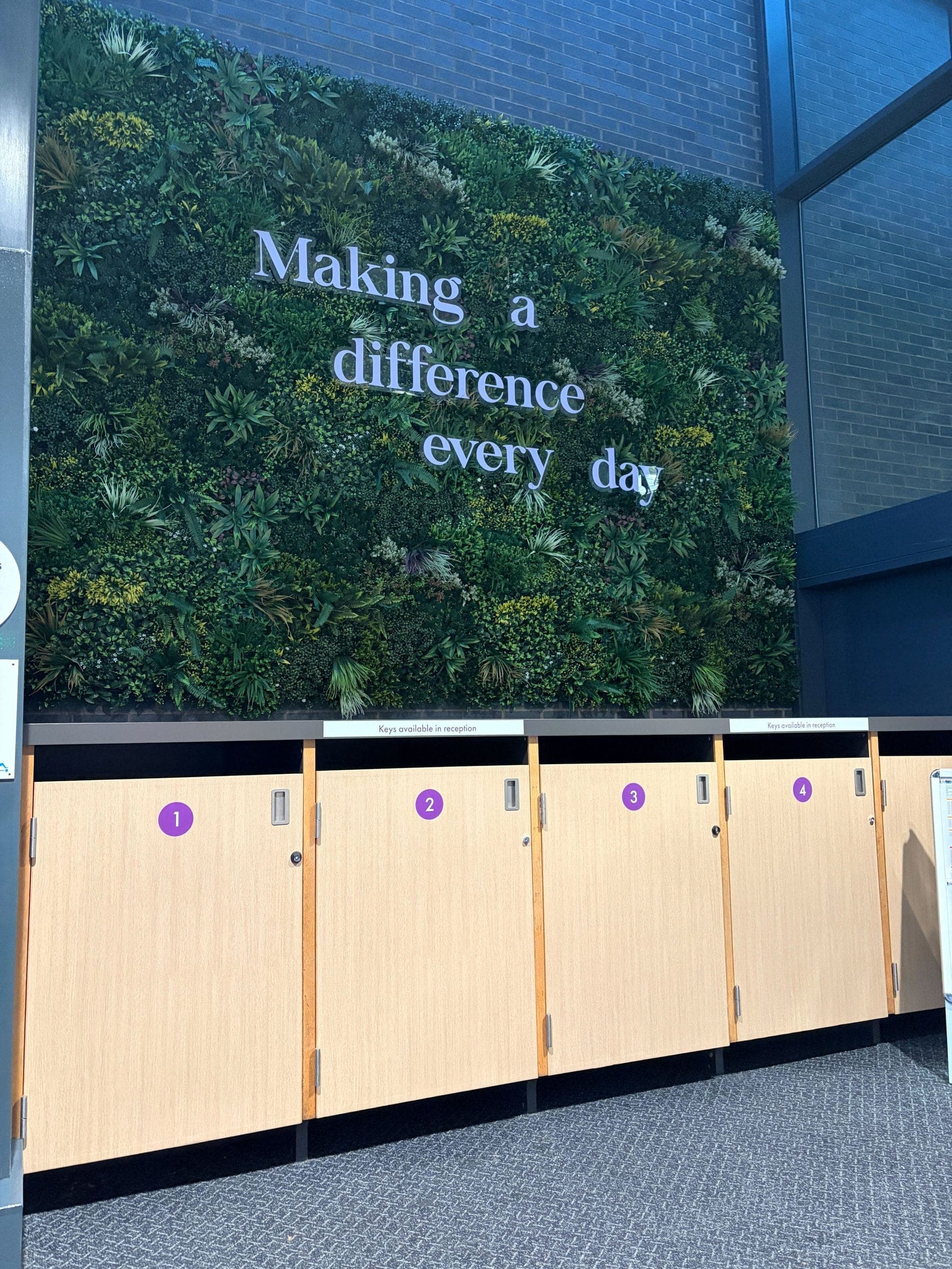 Living green wall with Making a difference every day messaging and oak locker units below