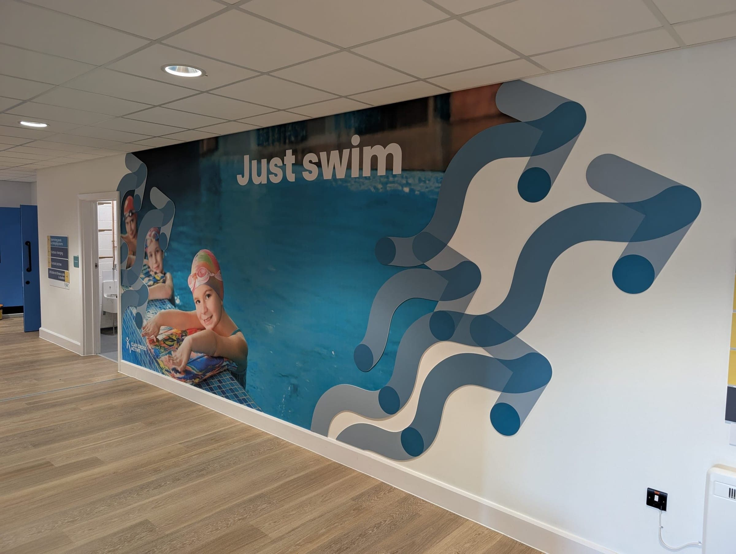 Just Swim branded wall mural with children in pool, Clay Cross Active corridor
