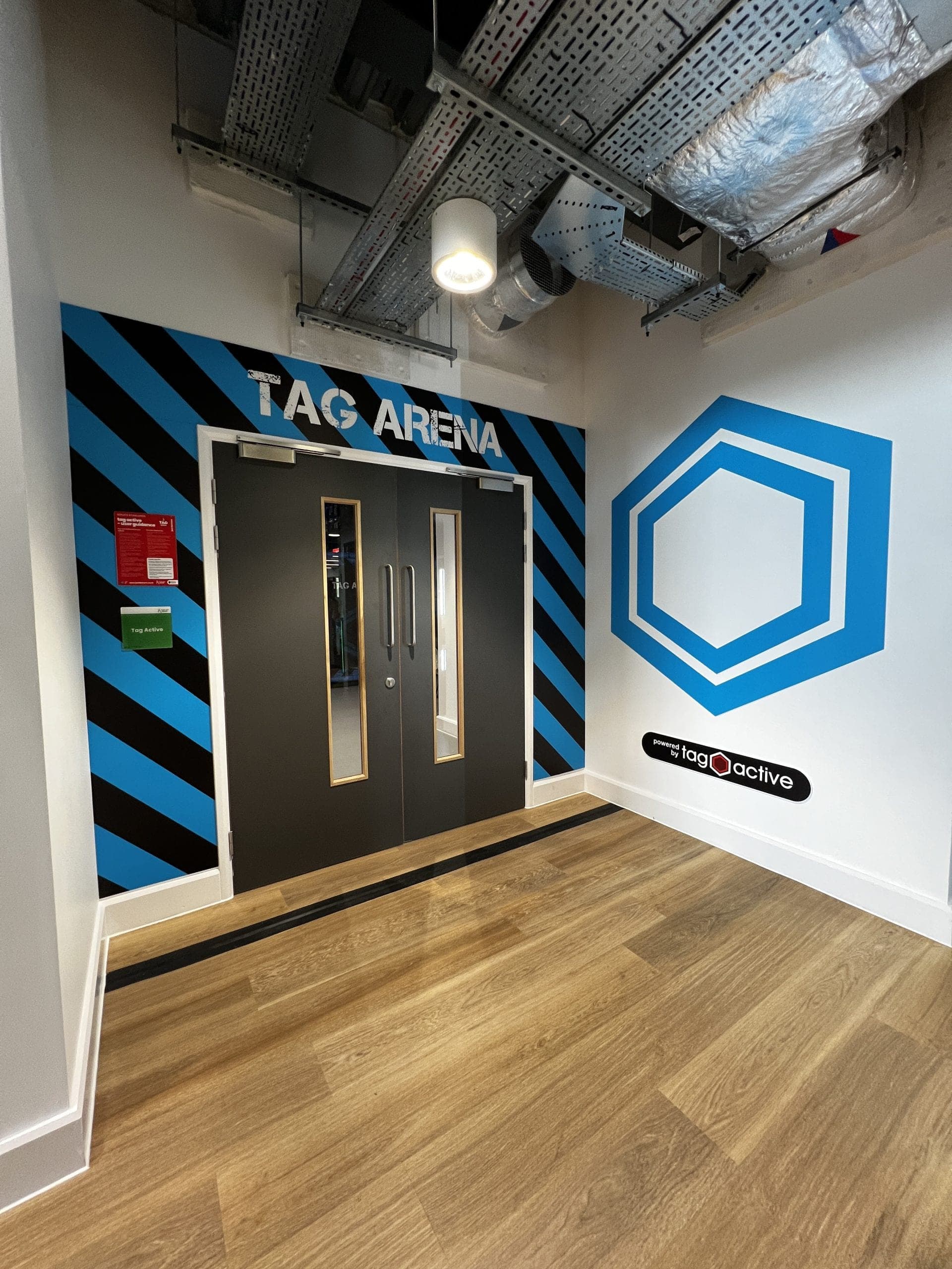 Tag Arena entrance with blue and black diagonal stripe wall graphics and hexagon logo