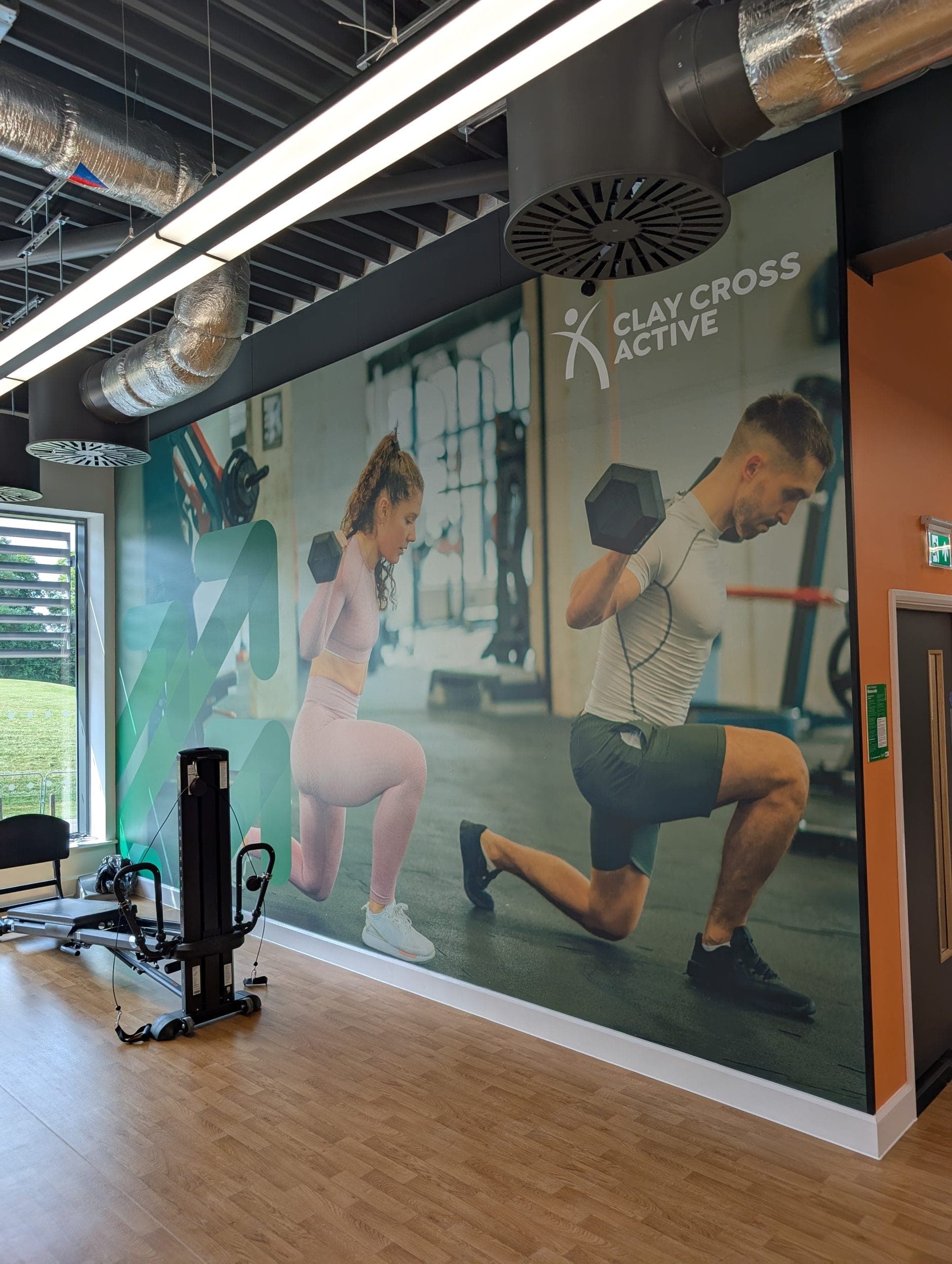 Clay Cross Active branded gym mural showing two people doing dumbbell lunges