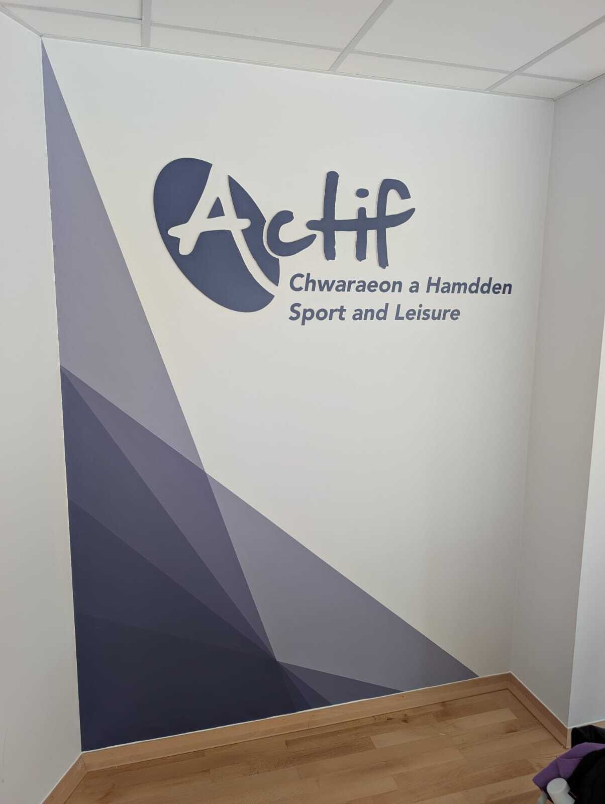 Room corner with Actif logo and geometric purple and grey diagonal wall mural