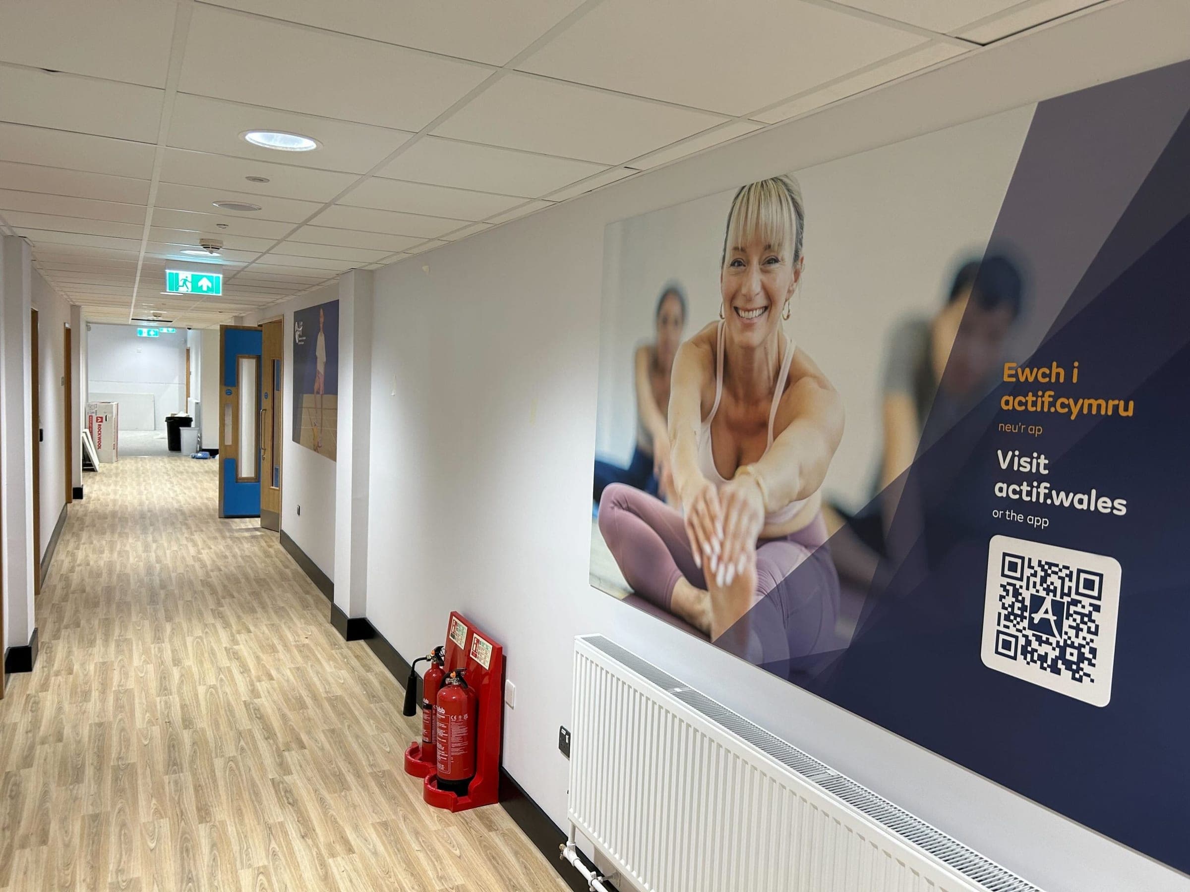 Long corridor with large Actif branded wall graphic promoting actif.wales