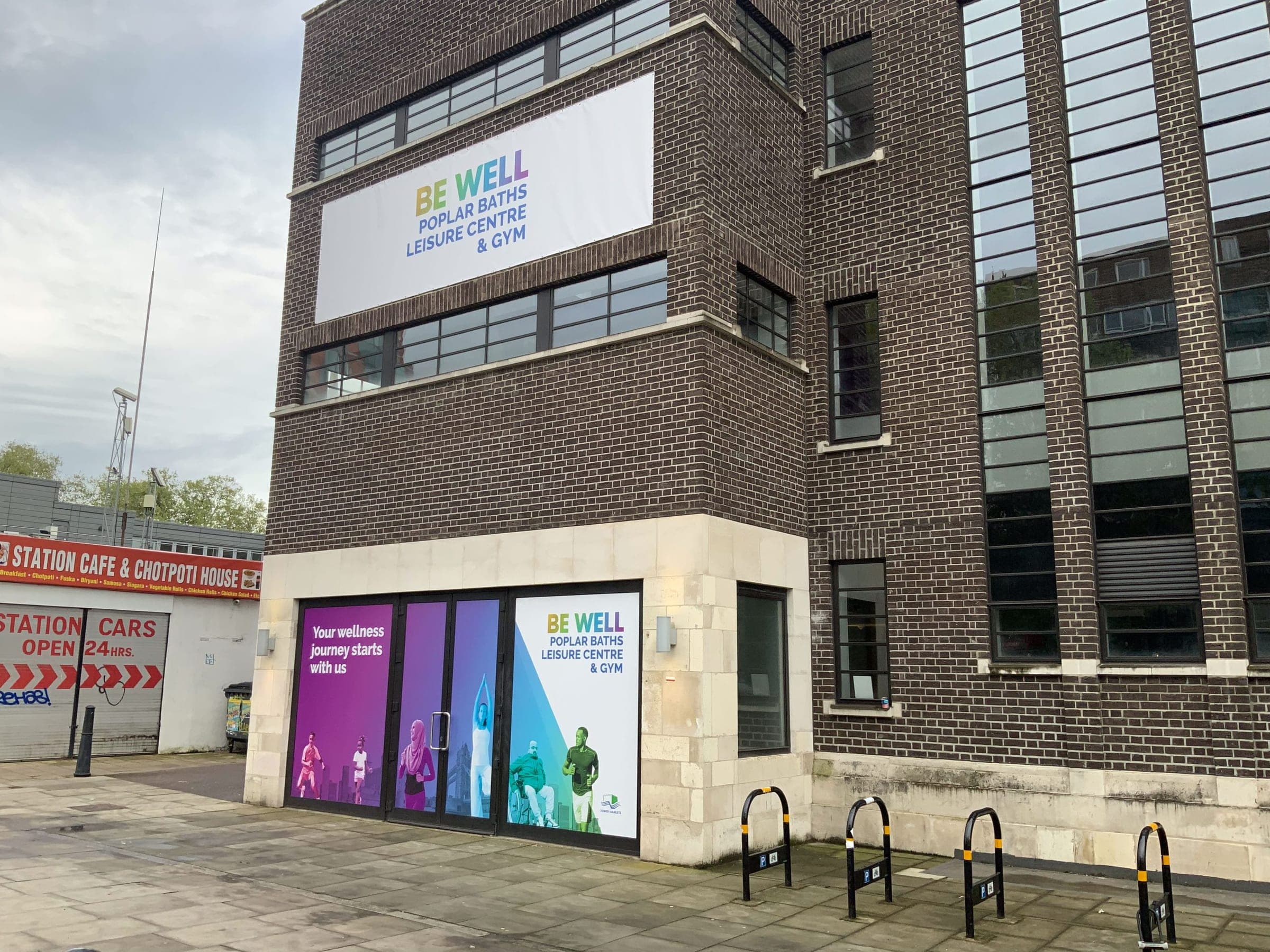 Poplar Baths corner with Be Well banner and colourful activity graphics
