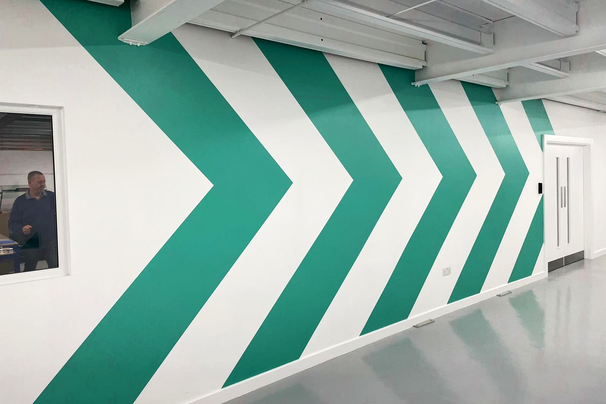 Corridor wall covered in large teal chevron arrow graphics pointing right