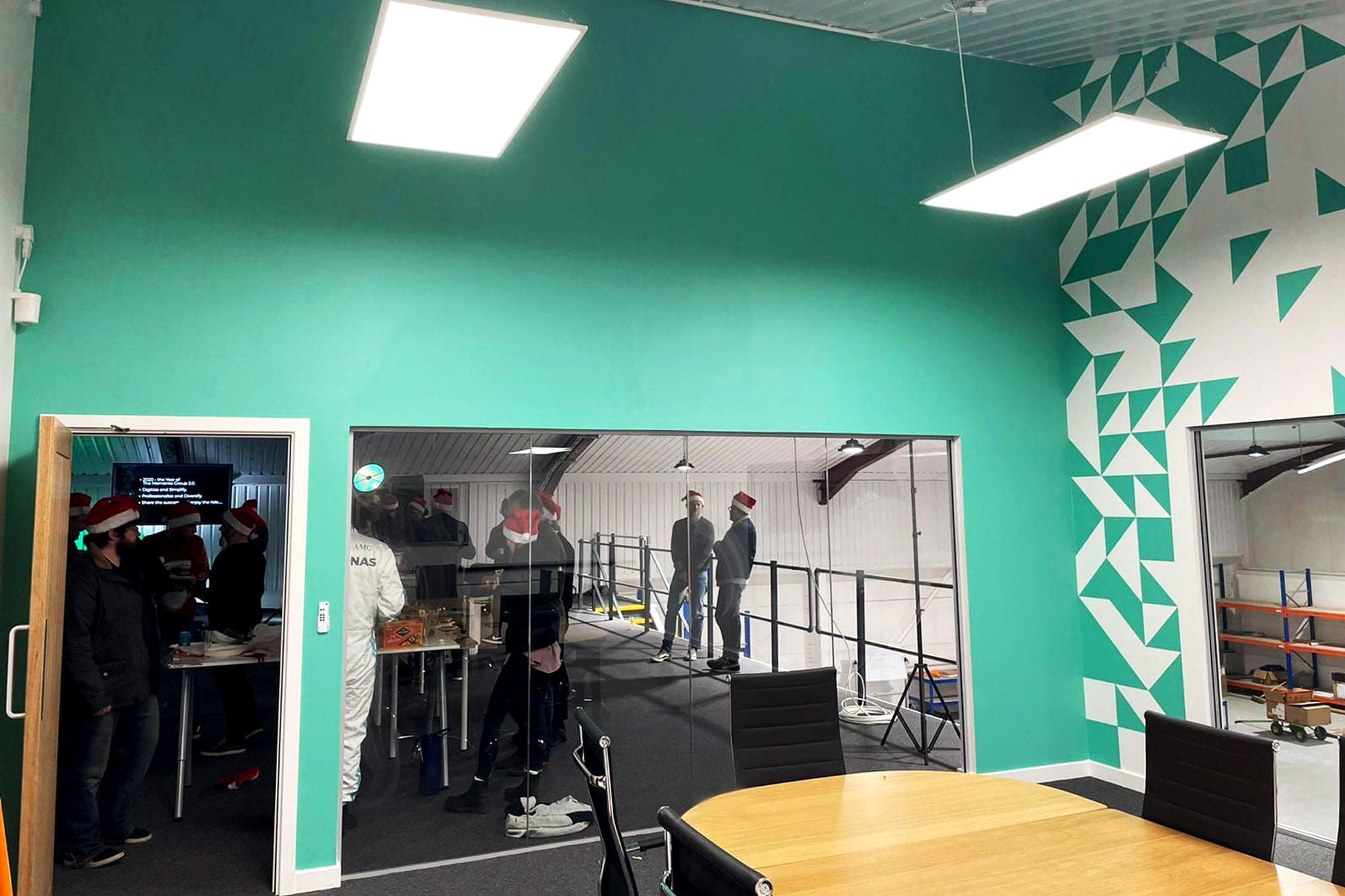 Open-plan office with teal walls and geometric triangle wall graphics