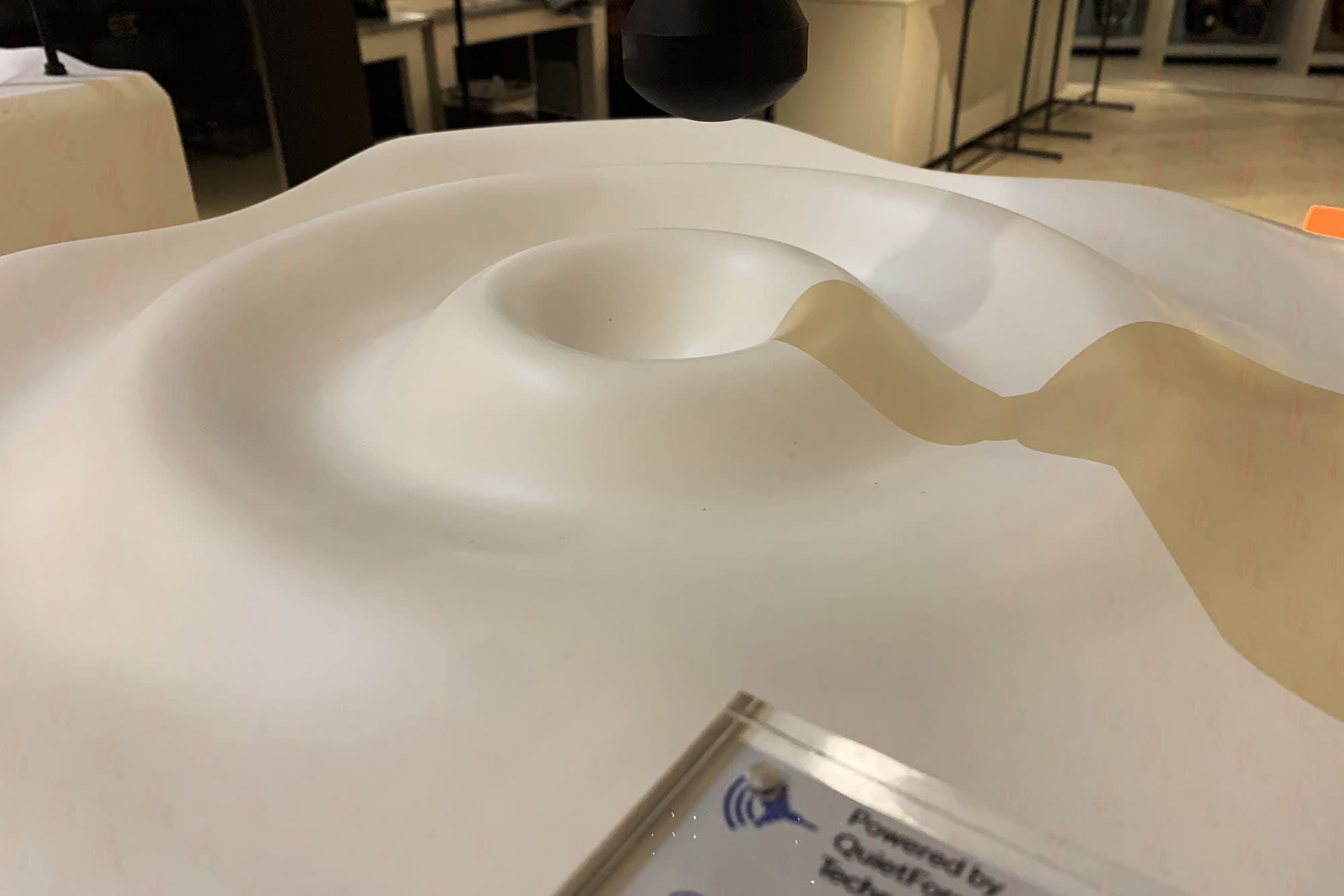 Macro close-up of the white sculpted foam display unit surface with a Theragun device head above